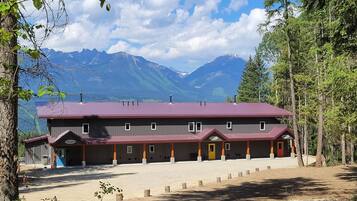 A lodge with a red roof, multiple rooms, and a view of mountains.