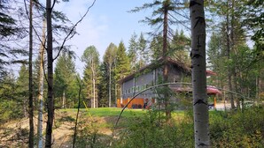 Une maison moderne à deux étages, entourée d’une forêt.