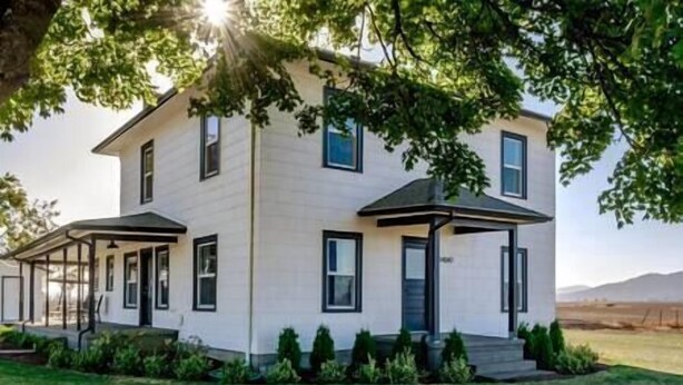 A two-story house with a covered porch and a small front yard. - Updated Farmhouse with lots of outdoor space and beautiful views! (Linn County)