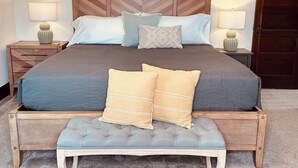 Una camera da letto ordinata con un letto grande, due comodini, una panca e una porta.