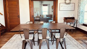 Una sala da pranzo con tavolo e sedie in legno, un lampadario e vista sull'area soggiorno.