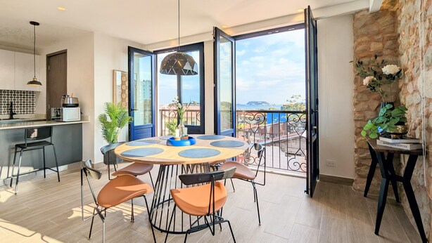 A modern kitchen with a dining area, large windows, and a view of the city. - La Cuadra by Wynwood House (Panama City)
