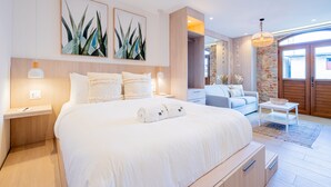 A modern bedroom with a large bed, bedside tables, a nightstand, a dresser, a small table with a bowl, and a hanging light fixture. - La Cuadra by Wynwood House (Panama City)