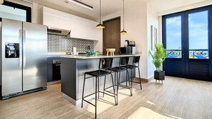 A modern kitchen with a built-in island, stainless steel appliances, and black bar stools. - La Cuadra by Wynwood House (Panama City)