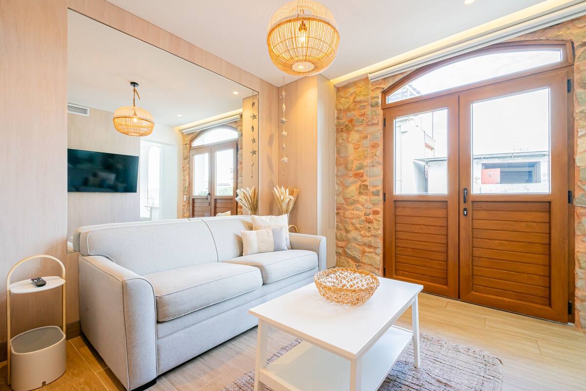 A modern living room with a sofa, a coffee table, a TV, and a large wooden door.