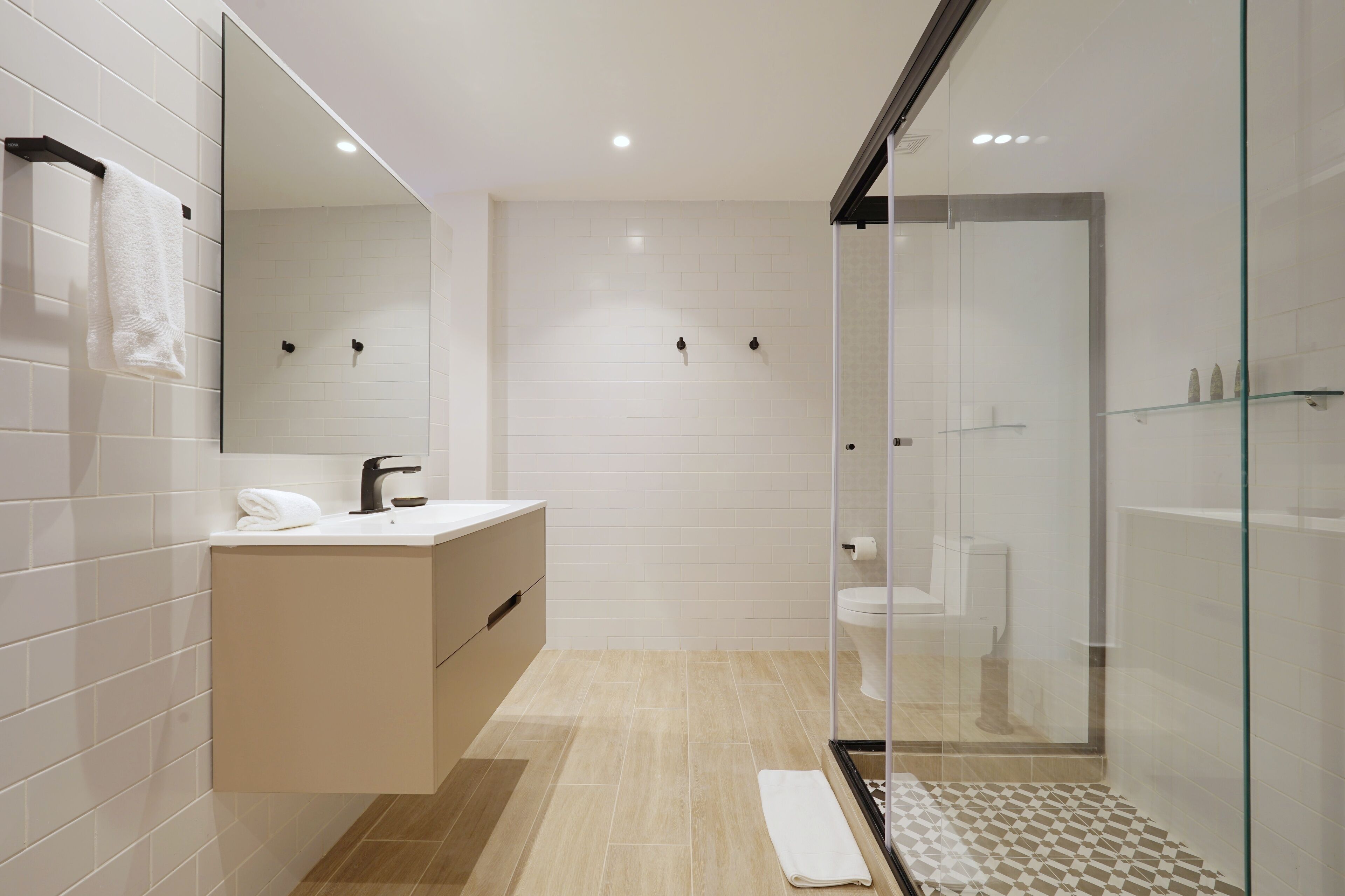 Une salle de bain moderne avec une douche à parois de verre, un lavabo blanc et un grand miroir.