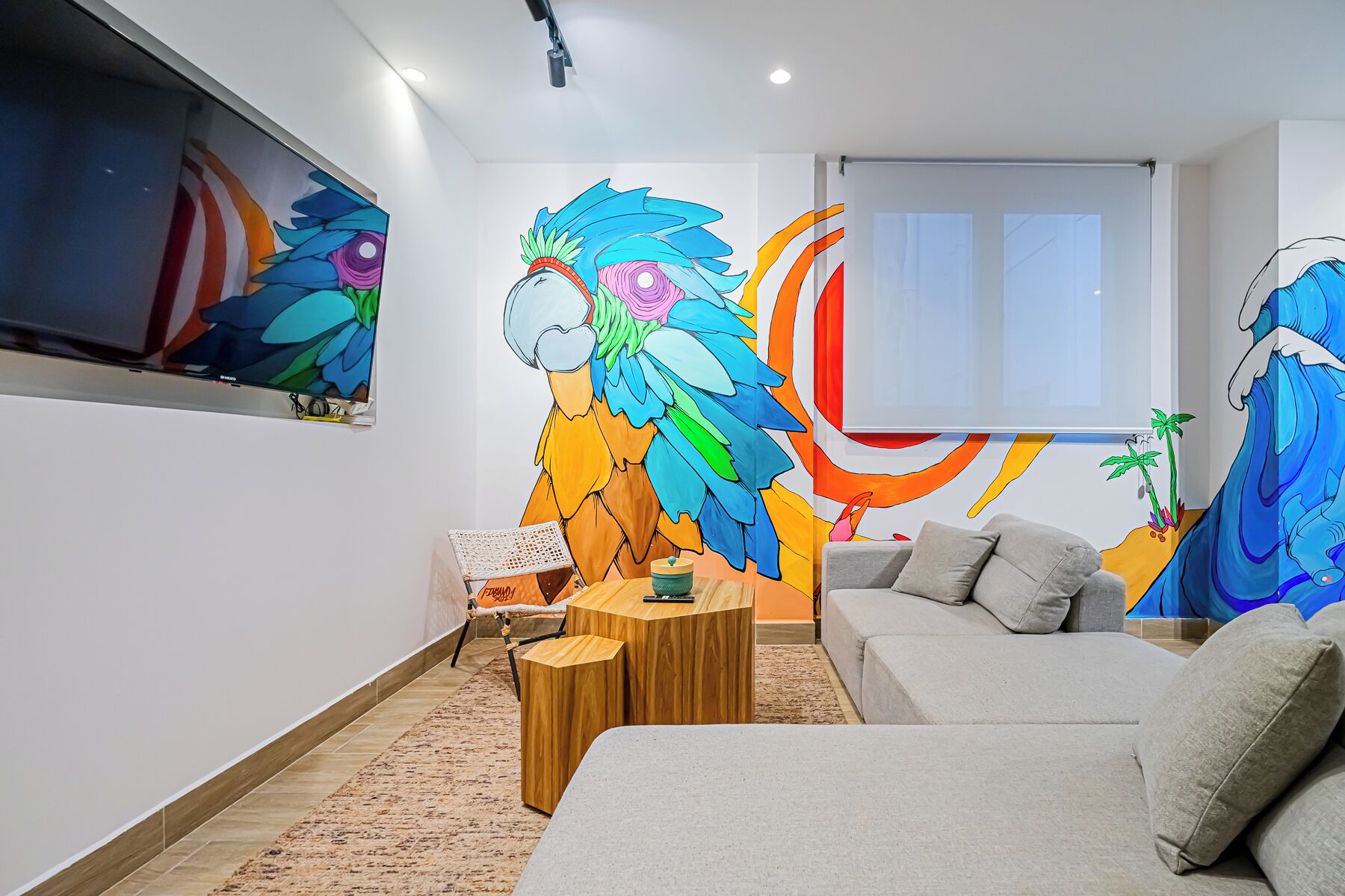 Una sala de estar moderna con un mural grande en la pared, un sofá, una mesa de centro y un televisor.