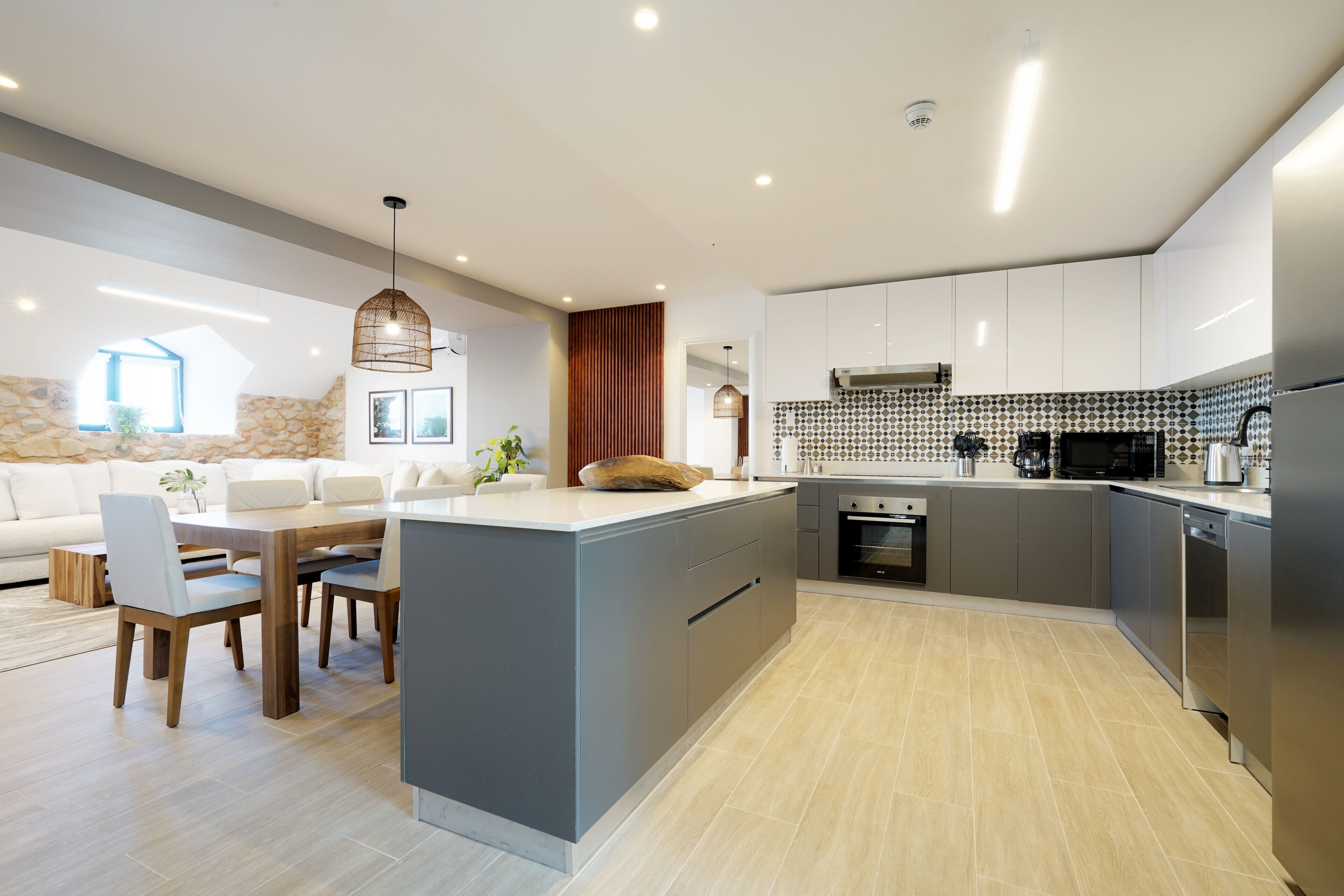A modern kitchen with a central island, built-in appliances, and a dining area with a sofa and chairs.