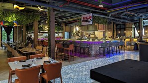 A modern restaurant with a sushi bar, bar seating, and a mix of indoor and outdoor dining areas. - La Cuadra by Wynwood House (Panama City)