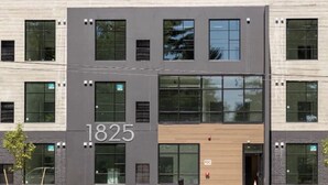 A modern building with the number 1825 on its facade, featuring large windows and a mix of dark and light materials. - Cozy, Eclectic 1 BR Condo w/Rooftop Hot Tubs, Dog Friendly! (Traverse City)