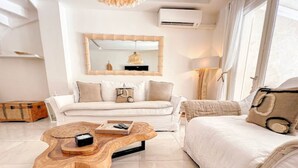 Una sala de estar moderna con un sofá blanco, una mesa de centro de madera y un espejo grande.