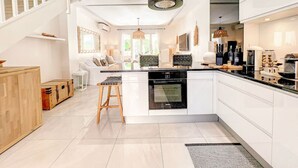 Una cocina moderna con armarios blancos, una isla central y un taburete de madera.