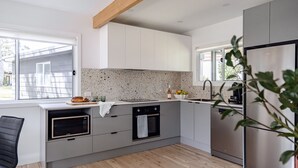 A modern kitchen with white cabinetry, a speckled backsplash, and stainless steel appliances. - Little Miss Sunshine (Burrill Lake)