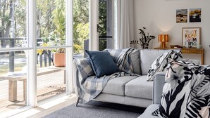 A modern living room with a grey sofa, a black and white patterned throw, and a wooden coffee table. - Little Miss Sunshine (Burrill Lake)