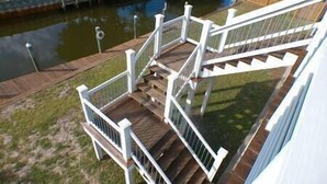 A wooden deck with white railings leading to a staircase. - Great Escape -2 Br 2Ba Waterfront Bay St Louis MS (Hancock County)
