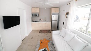 Una sala de estar moderna con un sofá blanco, una mesa de centro y un televisor de pantalla plana montado en la pared.