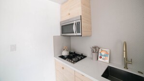 Una cocina con microondas, estufa a gas y un lavamanos.