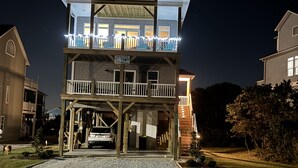 A multi-story building with a covered entrance and a balcony with lights. - Amazing views, short walk to the beach, Pup friendly home in Surf City, NC! (Surf City)