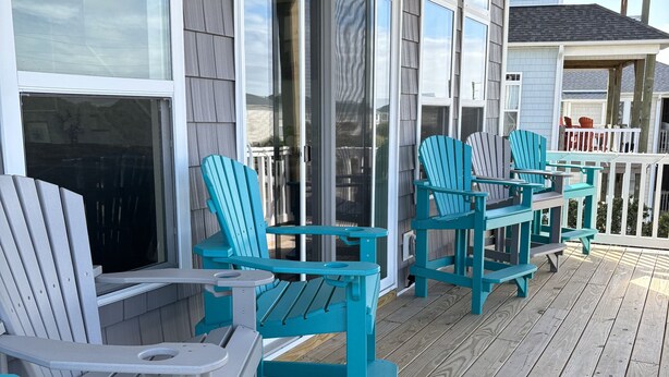 A covered deck with outdoor seating and a wooden railing. - Amazing views, short walk to the beach, Pup friendly home in Surf City, NC! (Surf City)