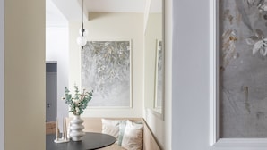 A modern interior with a round dining table, a sofa with cushions, a hanging light fixture, and a large abstract painting on the wall. - Luxury Piata Romana 2BR Urban Sanctuary by HOLT (Bucharest)
