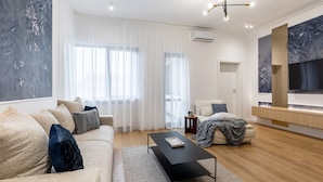 A modern living room with a sofa, coffee table, and a TV mounted on the wall. - Luxury Piata Romana 2BR Urban Sanctuary by HOLT (Bucharest)