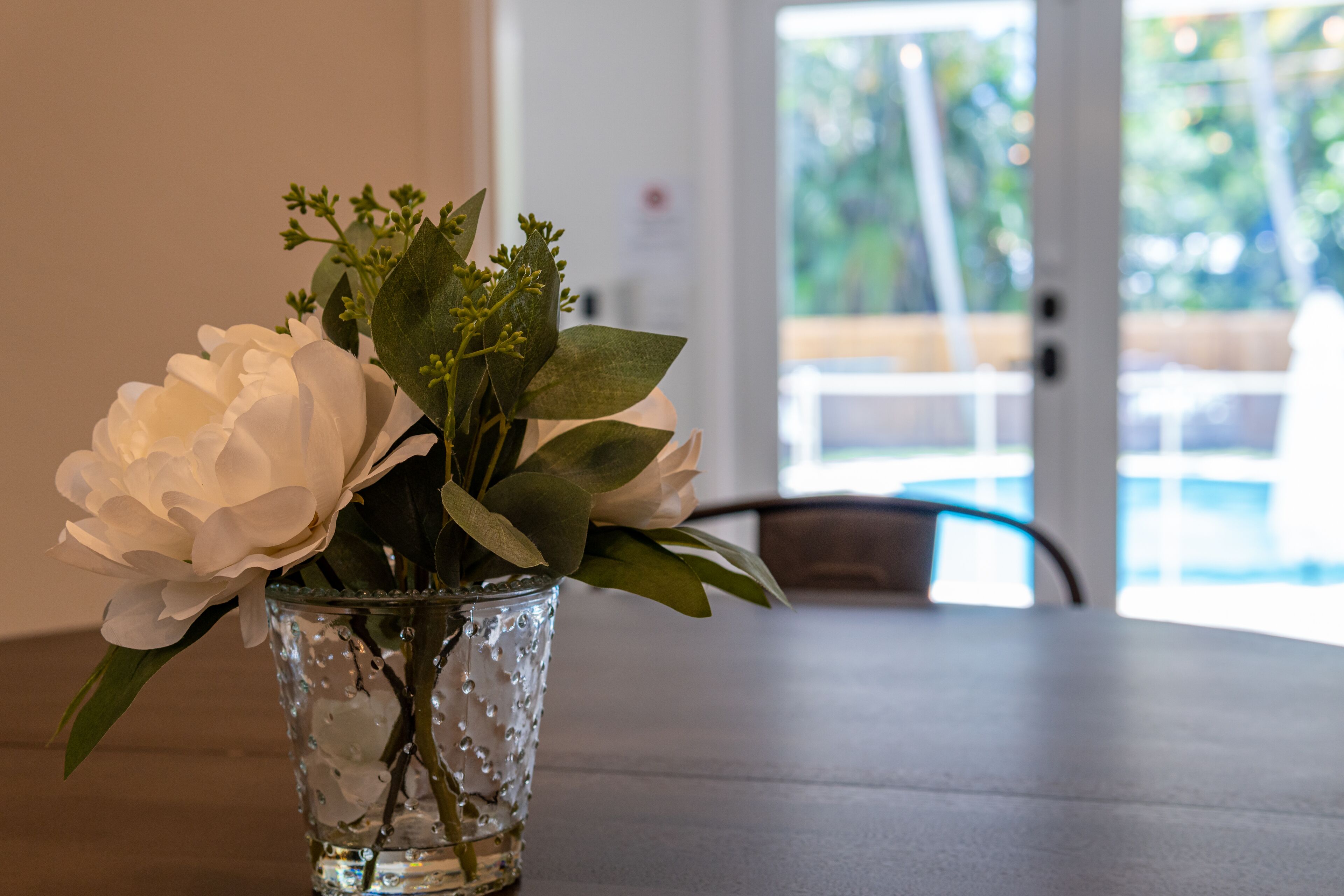 A glass vase with white flowers on a table.