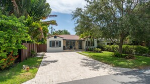 A residential house with a paved driveway, a front porch, and a well-maintained lawn. - Victoria Park Oasis with Heated Pool  (Fort Lauderdale)