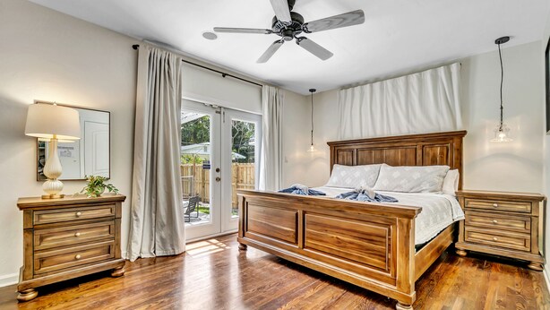 A bedroom with a wooden bed, a ceiling fan, a nightstand, and a dresser. - Victoria Park Oasis with Heated Pool  (Fort Lauderdale)