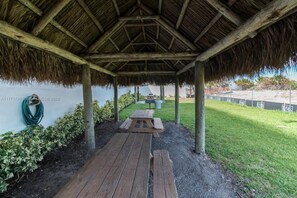 An outdoor covered patio with wooden benches and a thatched roof. - Spacious Beachfront Retreat,
Family Friendly,
Free parking/Free Public Trolley (Miami Beach)
