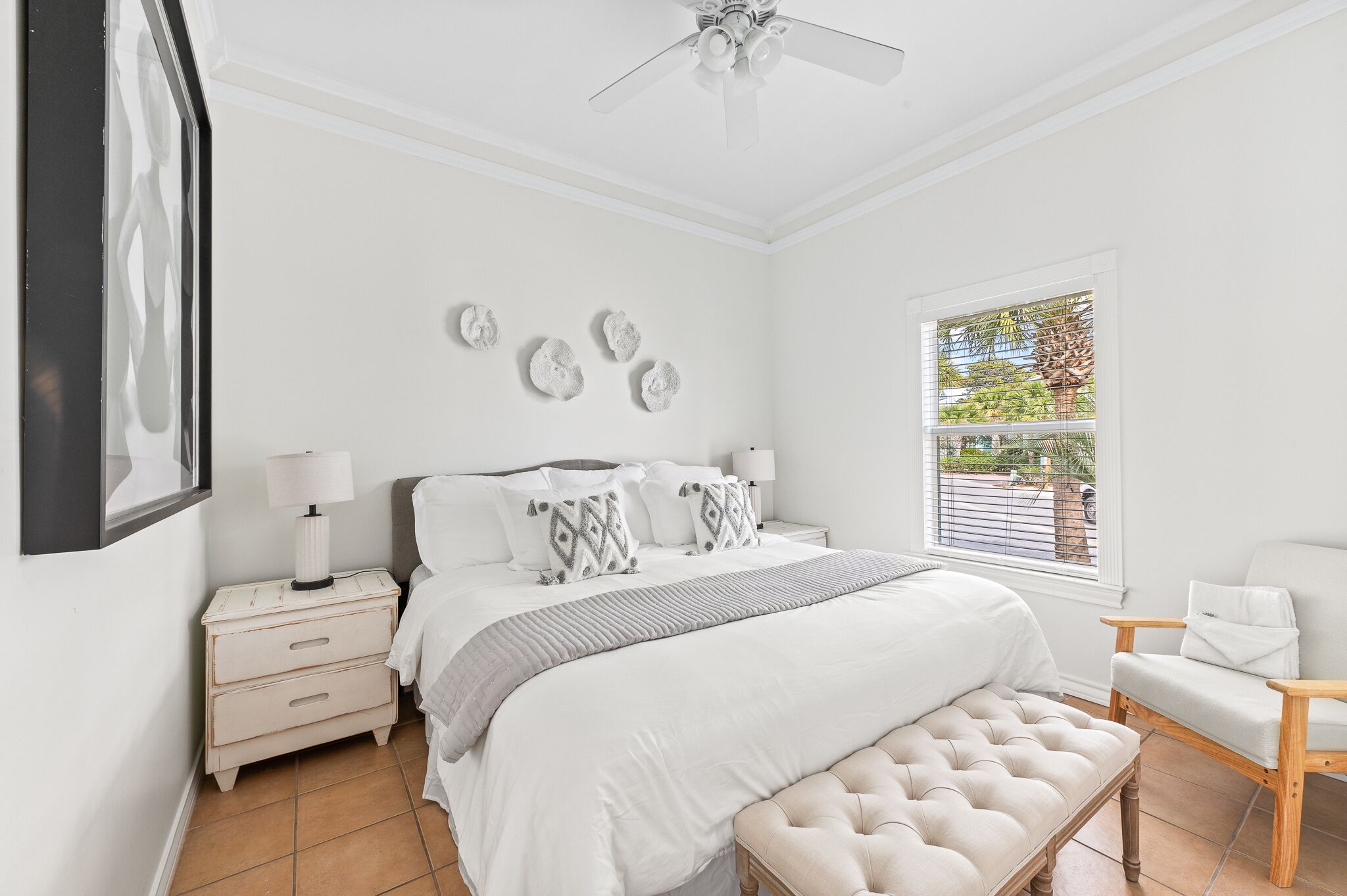 Un dormitorio con cama, mesitas de noche, una silla, una ventana y decoración en las paredes.