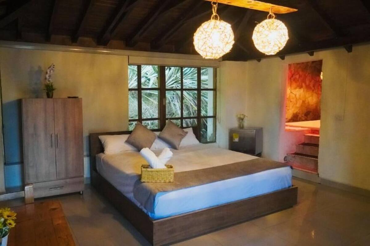 Un dormitorio con una cama grande, un armario de madera y un ventanal con vistas a zonas verdes.