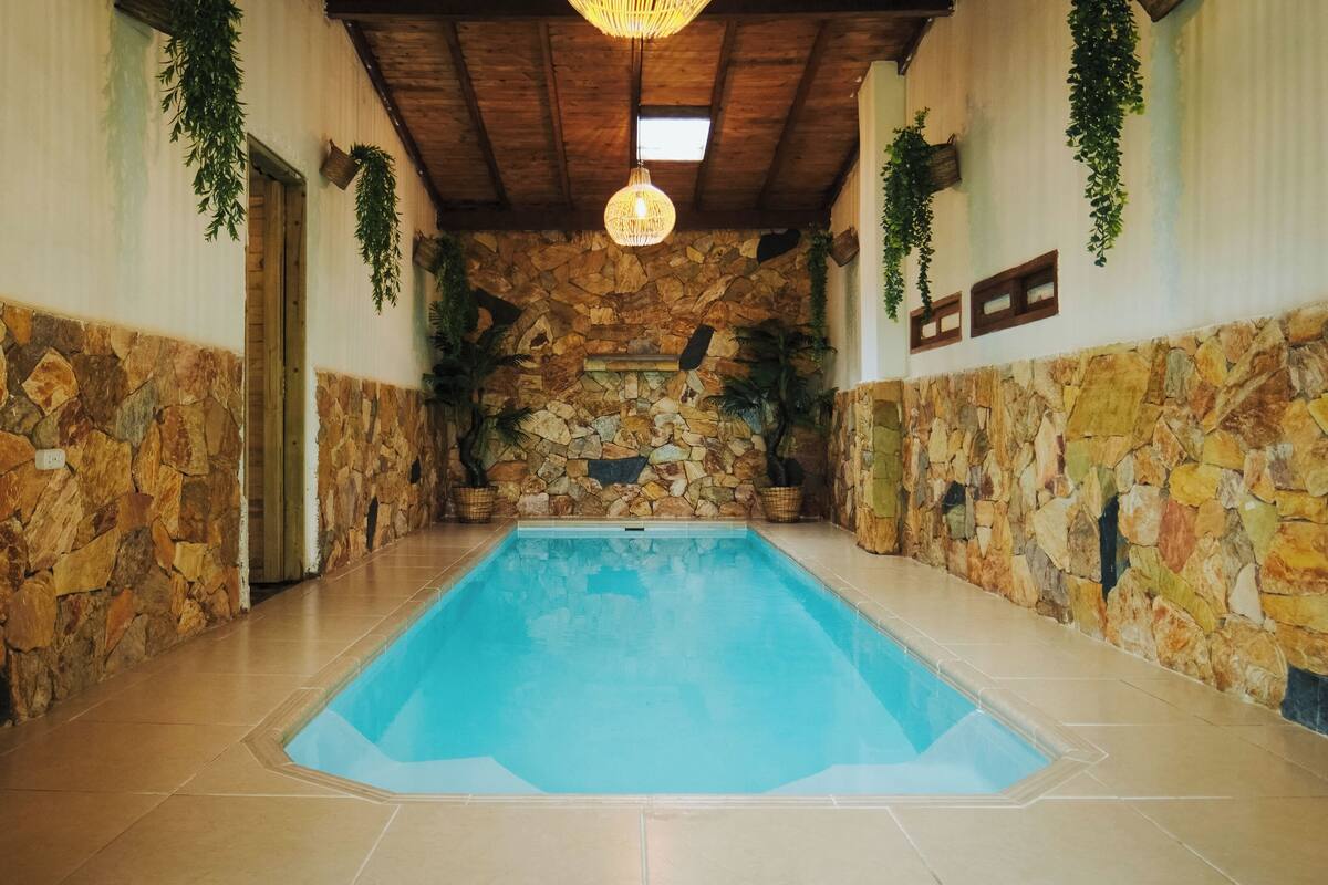 Una piscina con paredes de piedra y techo de madera.