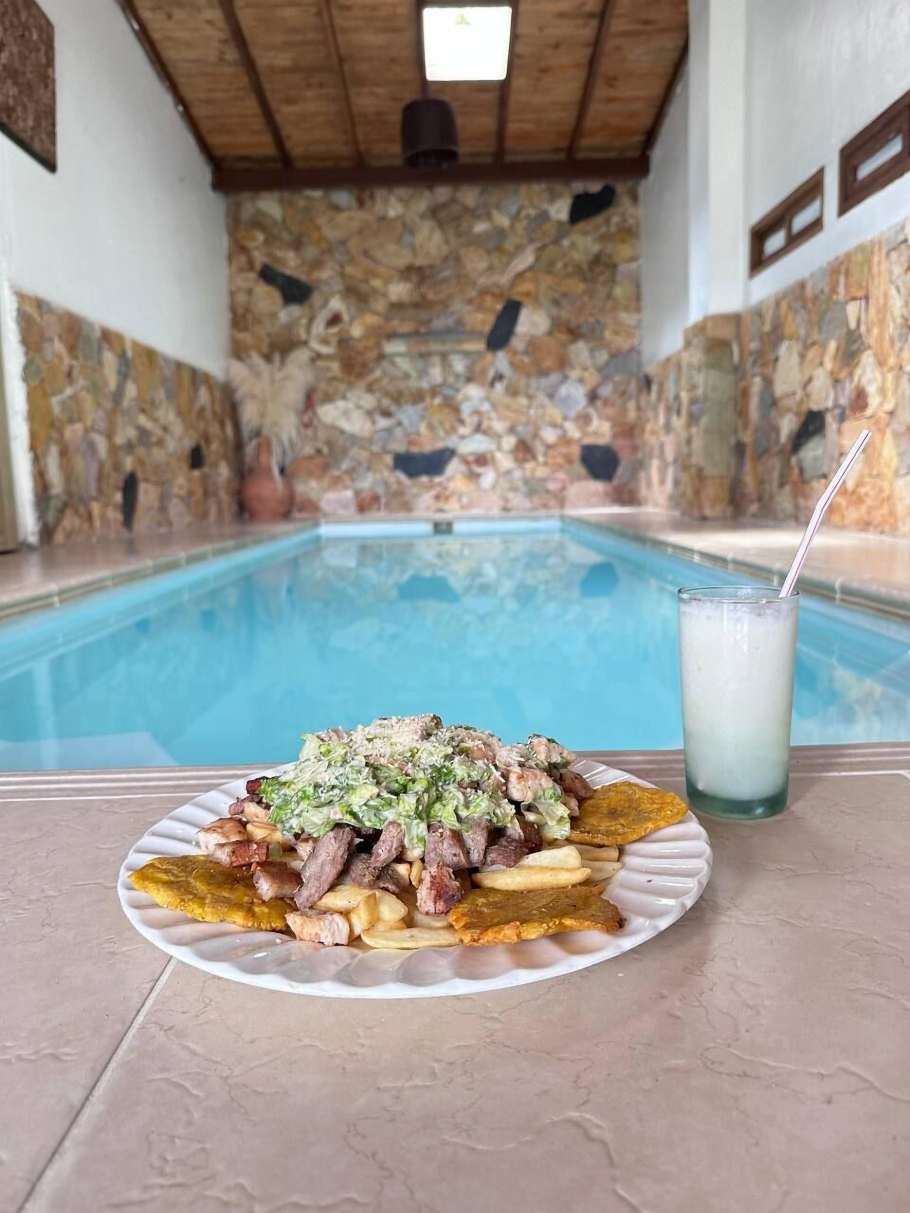 Une table à manger avec une assiette de nourriture, un verre de lait et une piscine en arrière-plan.