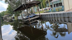 A dock with boats, a covered area, and a house with a porch.