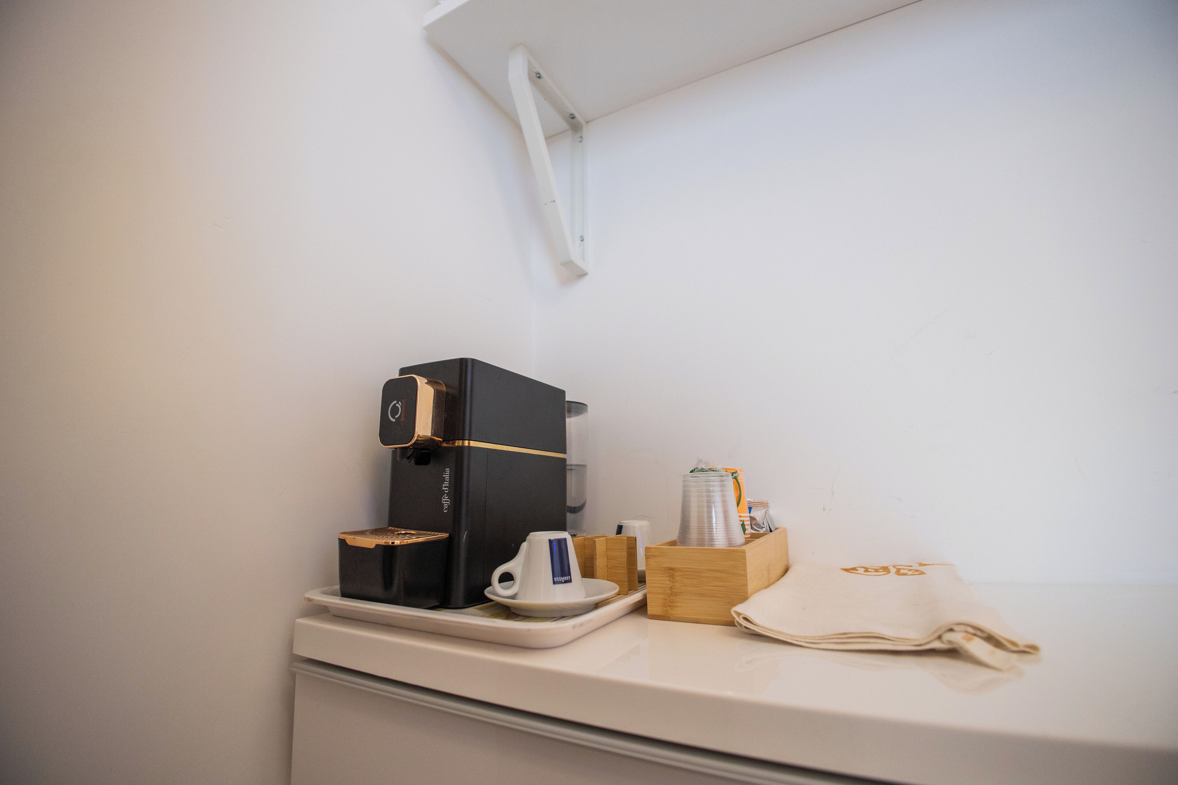Una máquina de café, una taza, un vaso y una servilleta sobre una encimera.