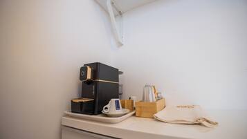 Una máquina de café, una taza, un vaso y una servilleta sobre una encimera.