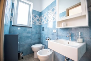Une salle de bain équipée de toilettes, d’un bidet et d’un lavabo.