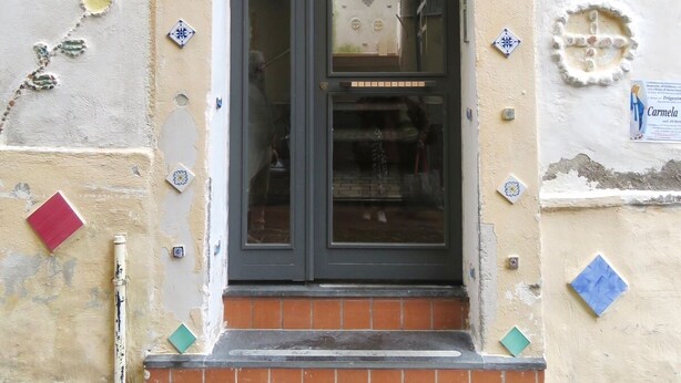 A building entrance with a dark door, a tiled wall, and numbered plaques. - Holiday Home Amalfitana Limone (Molina)