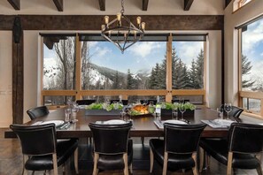 A dining area with a large table, black chairs, and a chandelier.