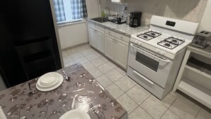 A compact kitchen with white cabinets, a gas stove, a built-in oven, and a sink.