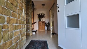 Un pasillo con pared de piedra, un mueble de madera con plantas decorativas y suelo de baldosas.
