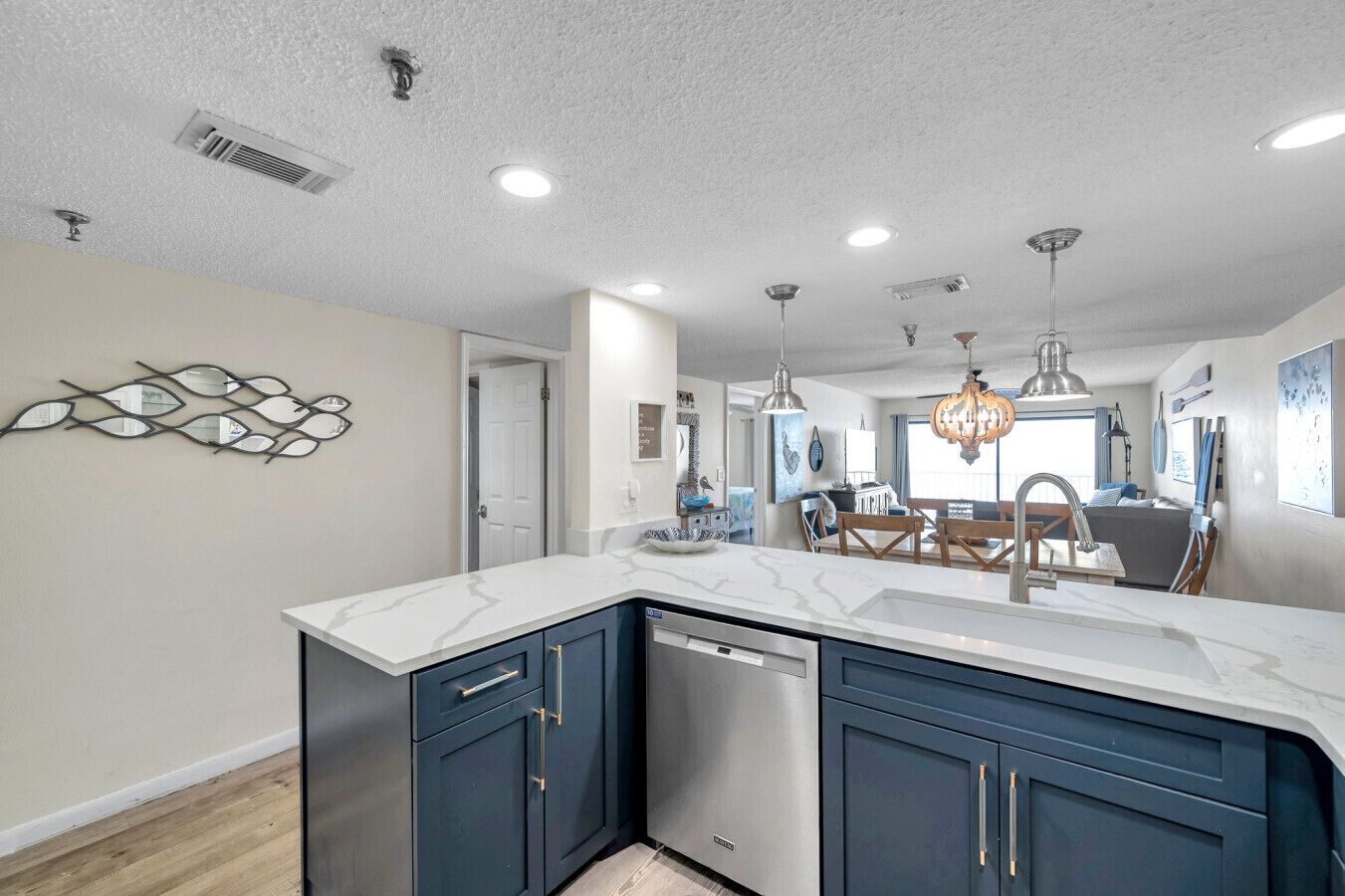 A modern kitchen with a central island, built-in dishwasher, and a dining area with a chandelier.