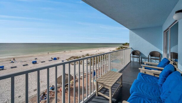 A balcony with a view of the beach, a table, and two chairs. - Sand Dollar #308 Beachfront 3 bedroom (Indian Shores)