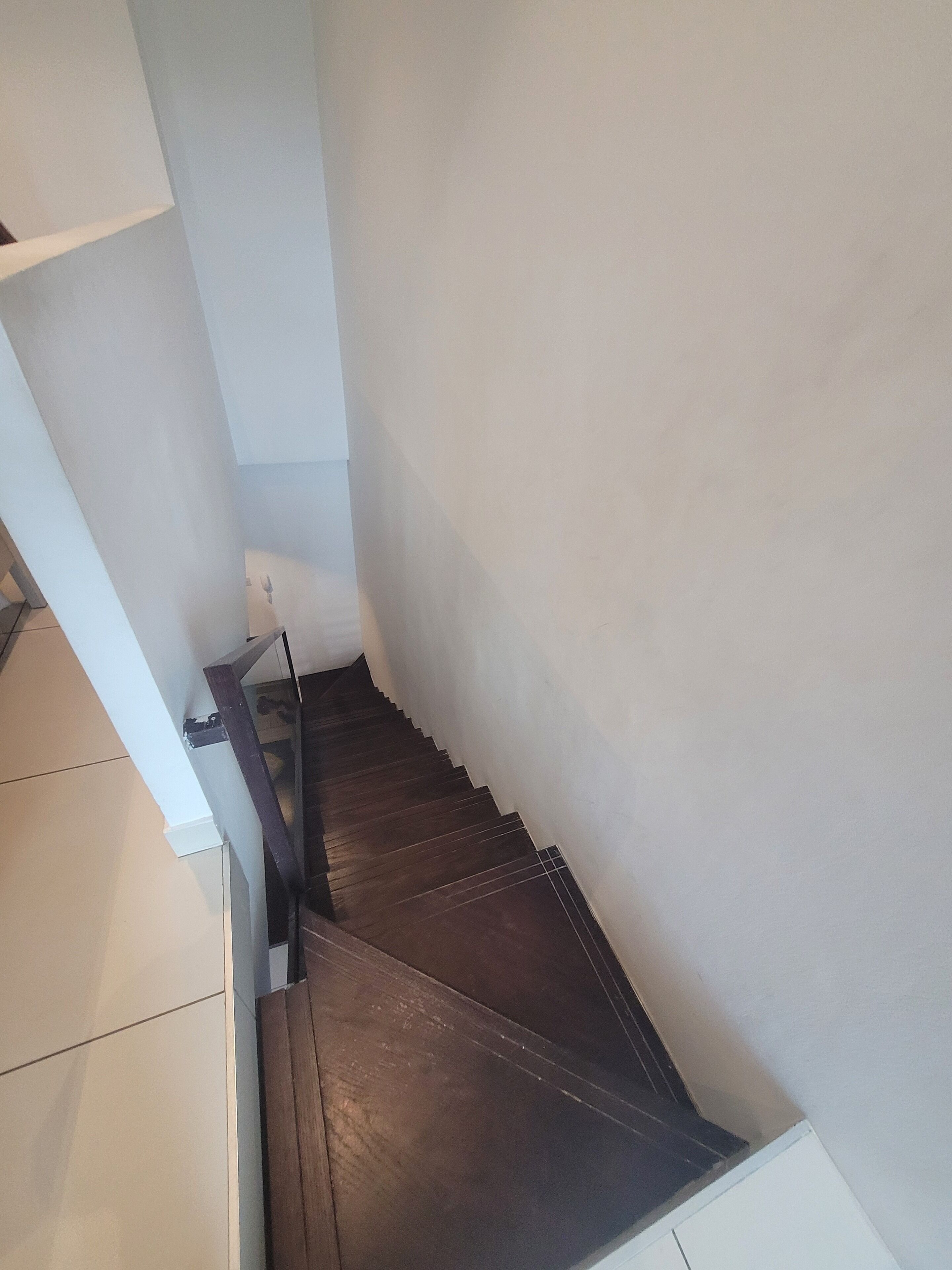 A staircase with dark wooden steps and white walls.