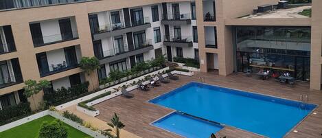 Un edificio moderno con piscina rodeada de césped verde y jardineras.