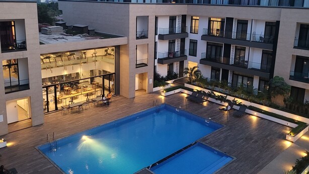 Ein modernes Hotel mit einem zentral gelegenen Schwimmbad, Außenbereich und mehreren Balkonen.
