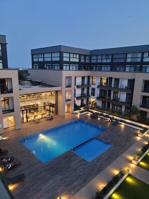 Un hotel moderno con una piscina central, asientos al aire libre y varios balcones.