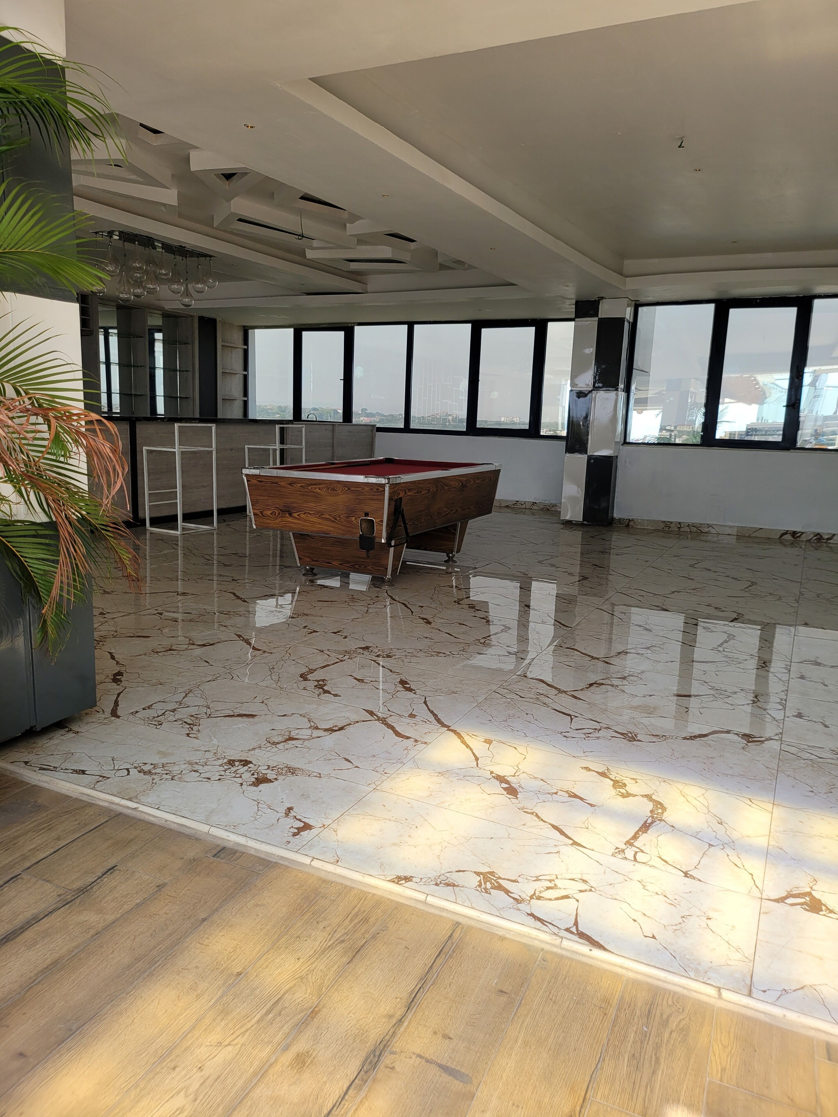 A spacious room with a pool table, large windows, and a view of the city.