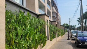 Ein modernes Gebäude mit Pflasterweg, einer begrünten Wand und abgestellten Autos.