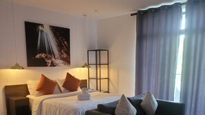 Ein modernes Hotelzimmer mit Bett, Sofa, Beistelltisch, Lampe und einem Gemälde an der Wand.